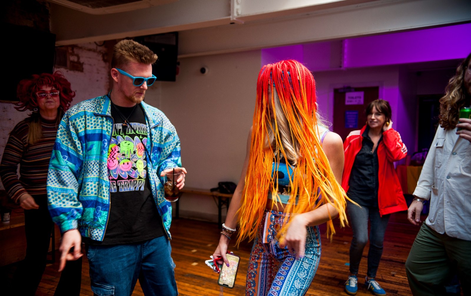 Guests dancing in colourful outfits and an orange fringed headdress